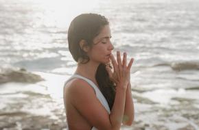 Vrouw die mediteert aan zee